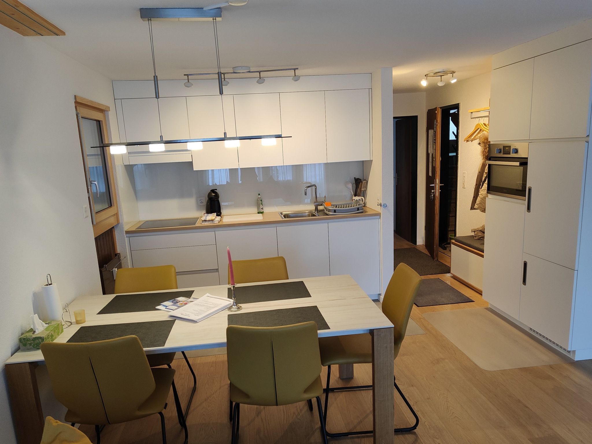 Une cuisine moderne avec des meubles blancs, un îlot central et un coin repas comprenant une table et des chaises.