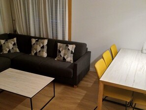 A living room with a sofa, a coffee table, and a dining table with chairs. - Nr. 20 - Haus Opal, (Grächen), by Interhome (Grächen)