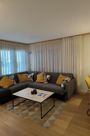 Ein Wohnzimmer mit einer Couch, einem Couchtisch und Vorhängen.