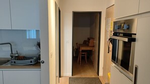 Una cocina moderna con estufa, horno y microondas integrados. Se ve un comedor con mesa y sillas a través de una puerta abierta.