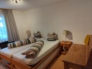 Ein Doppelbett mit gestreifter Bettwäsche, ein Nachttisch mit Lampe und ein Holzbeistelltisch.