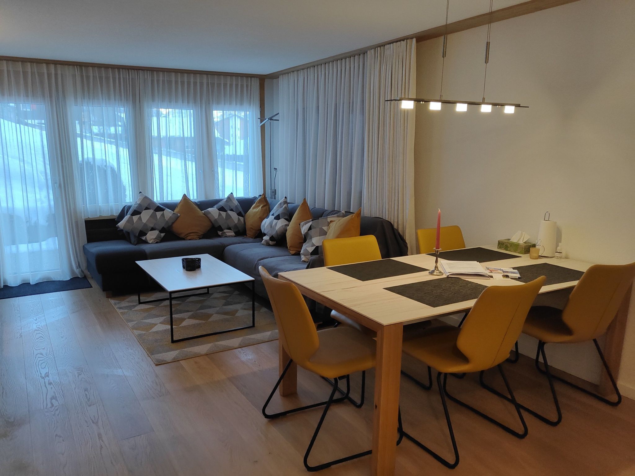 Un salon moderne comprenant un canapé, une table basse et une table à manger avec des chaises.