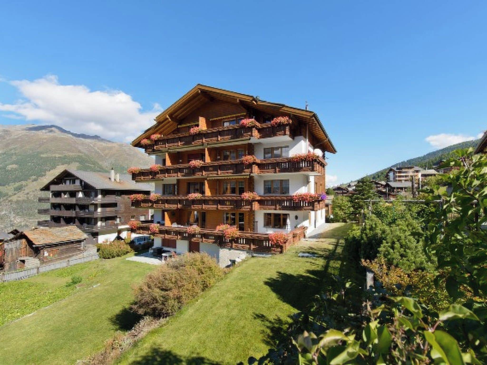A multi-story hotel with balconies, set in a mountainous area.