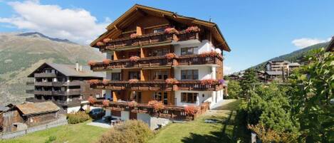A multi-story hotel with balconies, set in a mountainous area.