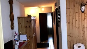 Ein schmaler Flur mit Holzkästen, einem kleinen Tisch mit Sprühflasche und einem Stuhl.