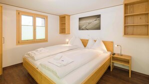 Ein hölzernes Bett mit weißen Leinen, ein Nachttisch mit einer Lampe und ein Bild an der Wand.