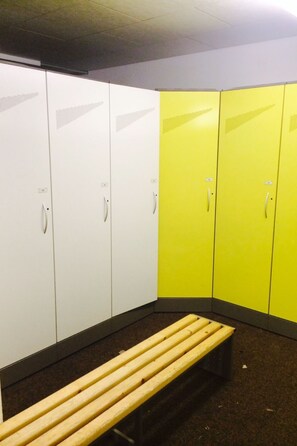 A locker room with white and yellow lockers, a bench, and a tiled floor. - Lunic, AZapartments.ch, B&B, (Grächen), 1057 by Interhome (Grächen)