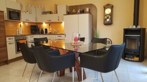 A modern kitchen with a glass dining table, black chairs, and a clock on the wall. - Silberblick, (Grächen), by Interhome (Grächen)