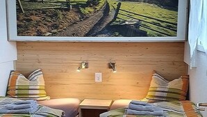 A room with two beds, a wooden headboard, and a framed picture of a landscape. - Silberblick, (Grächen), by Interhome (Grächen)