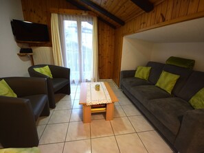 Ein Wohnzimmer mit einer Sofagarnitur, einem Couchtisch und einem flachbildfernseher an der Wand.