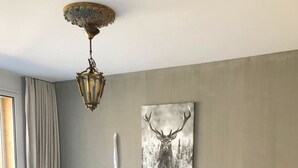 Een slaapkamer met een houten bed, een hertenbeeld aan de muur, een lamp en een nachtkastje.