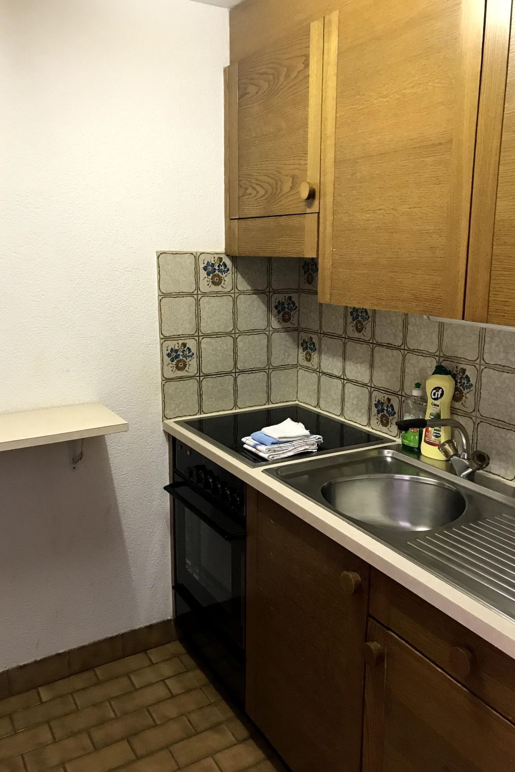 Una piccola cucina con lavello, mobili in legno e schienale piastrellato.