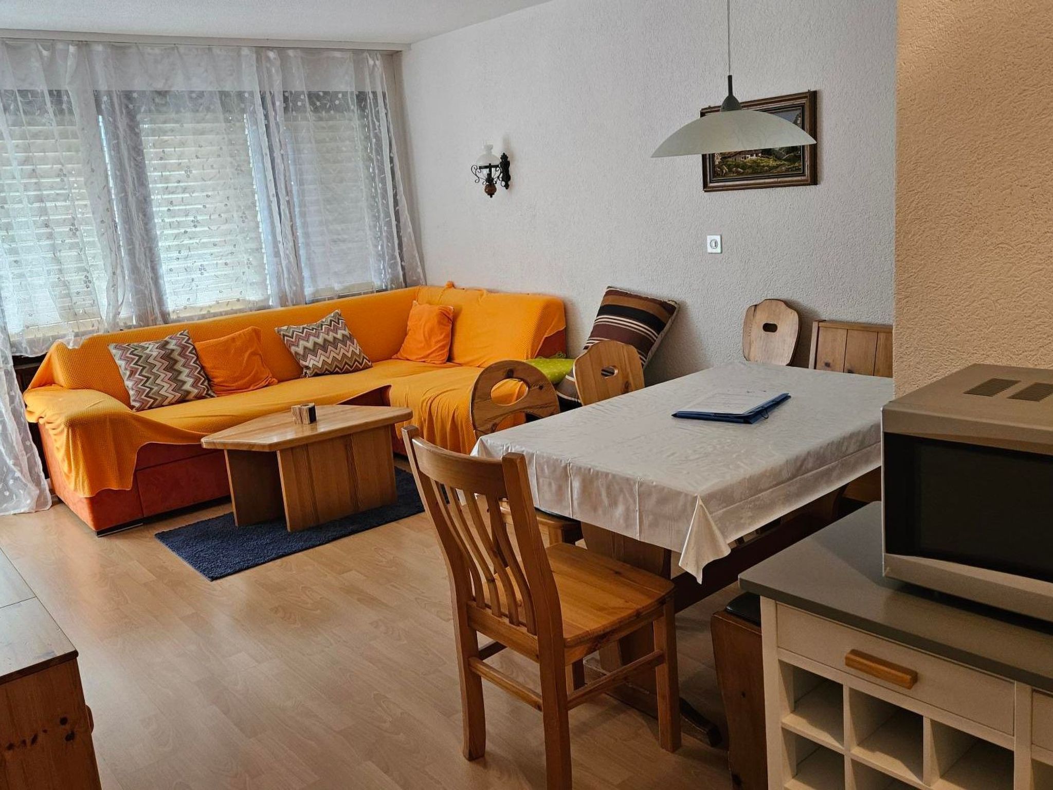 Uma sala de estar com sofá, mesa de jantar e televisão.