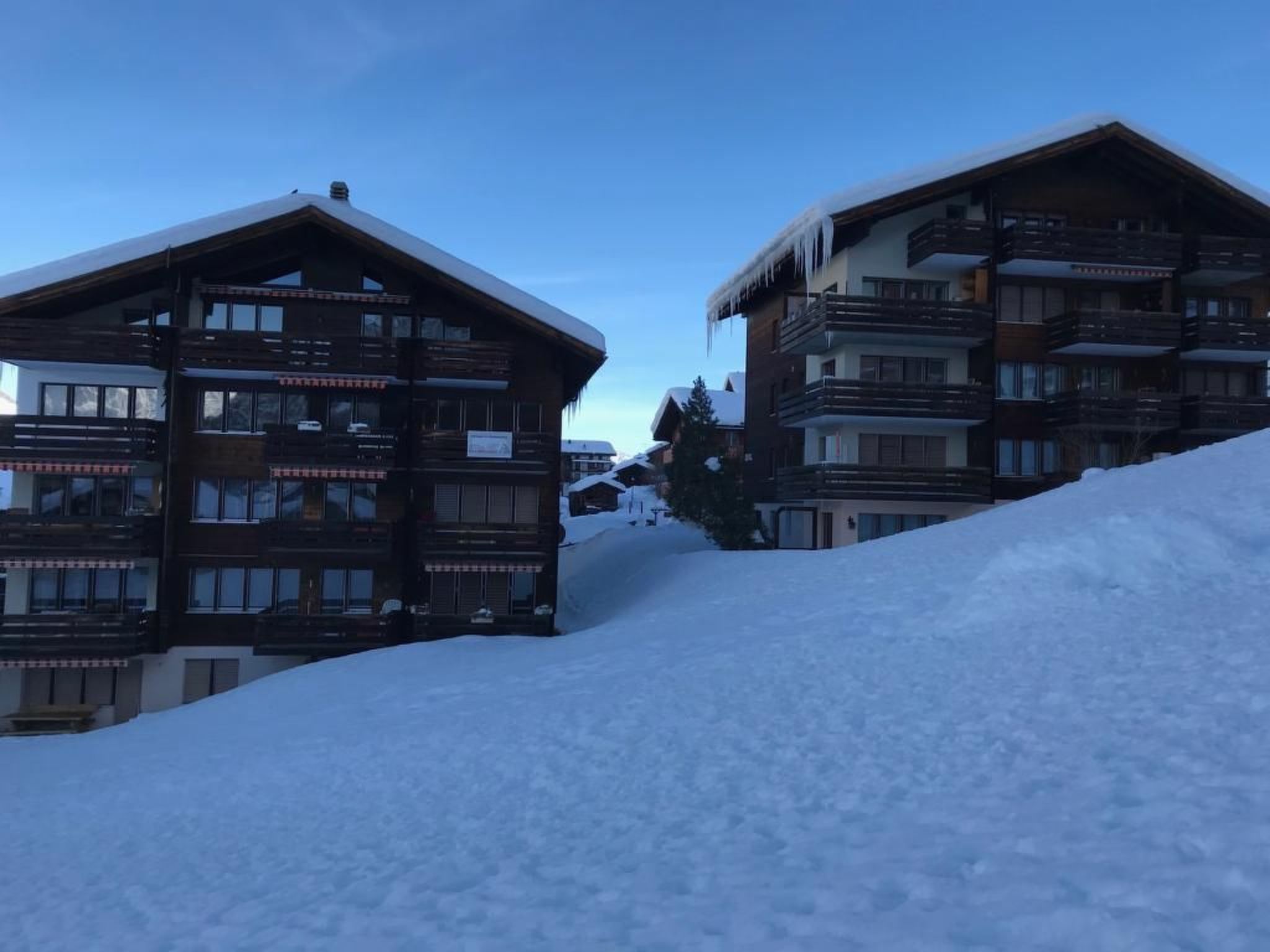 A wooden building with multiple balconies and a snow-covered slope.