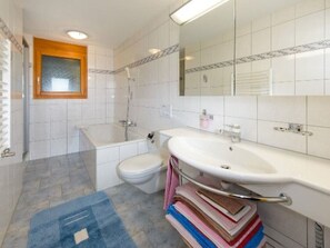 A bathroom with a bathtub, toilet, and sink. - Ferienwohnungen Schmiedstube 420, (Grächen), by Interhome (Grächen)