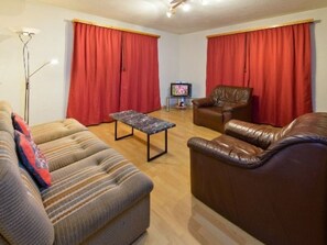 A living room with a sofa, a coffee table, a television, and two leather chairs. - Ferienwohnungen Schmiedstube 420, (Grächen), by Interhome (Grächen)
