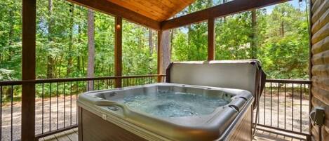 A hot tub on a wooden deck with a view of a forest.