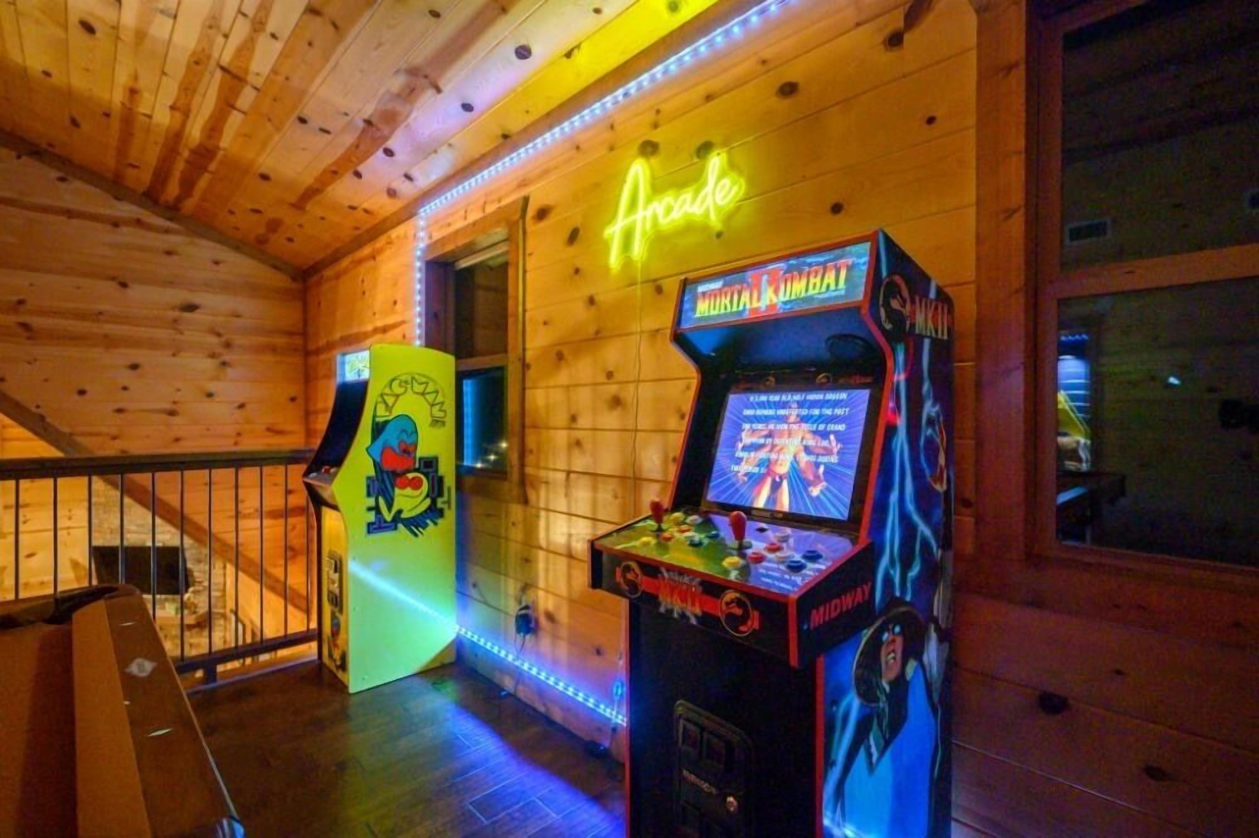 Een houten interieur met flipperspellen, waaronder Mortal Kombat, en een neonbord met de tekst 'Arcade'.