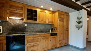 A kitchen with wooden cabinets, granite countertops, a dishwasher, and a hanging light fixture. - Goldblick, (Grächen), 1767+1034+2083 by Interhome (Grächen)
