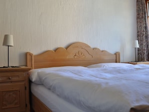 Ein Einzelbett mit Holz Kopfteil, ein Nachttisch mit Lampe und eine Kommode.