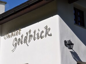 Ein Gebäude mit einem Schild, auf dem 'Chalet Goldblick' steht, und einer Wandleuchte.