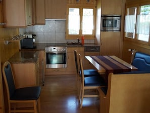 Eine kompakte Küche mit Herd, Backofen, Mikrowelle und einer Essecke mit Tisch und Stühlen.