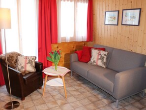 A cozy living room with a sofa, armchair, and a small table with a vase of flowers. - Ferienwohnungen Bel Air, (Grächen), 1292 & 1575 by Interhome (Grächen)