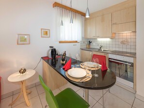 A compact kitchen with a dining area, equipped with a coffee maker, wine glasses, and a small table set for two. - Metropol A9, (Grächen), 1126 by Interhome (Grächen)