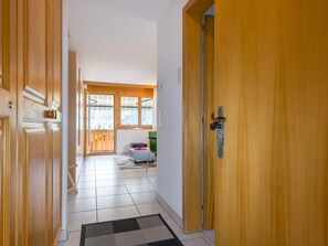 A hallway with wooden doors, a tiled floor, and a view of a room with a table and chairs. - Metropol A9, (Grächen), 1126 by Interhome (Grächen)