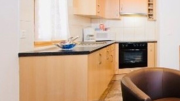 Une cuisine compacte comprenant un coin repas, un canapé et un fauteuil.