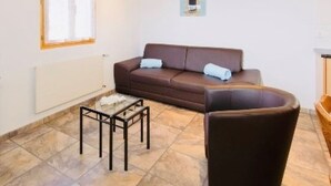 Un salon avec un canapé marron, une petite table et un fauteuil.