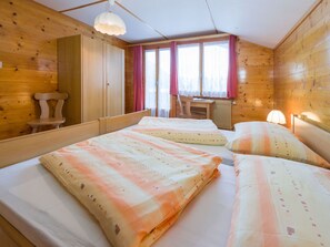 Ein Zimmer einer Holzjagdhaus mit zwei Betten, einem Schreibtisch und einem Stuhl.