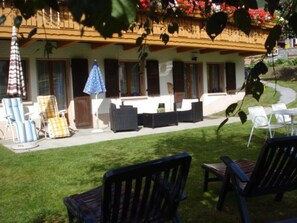 A patio area with outdoor furniture, a pool, and a building with a sloped roof.