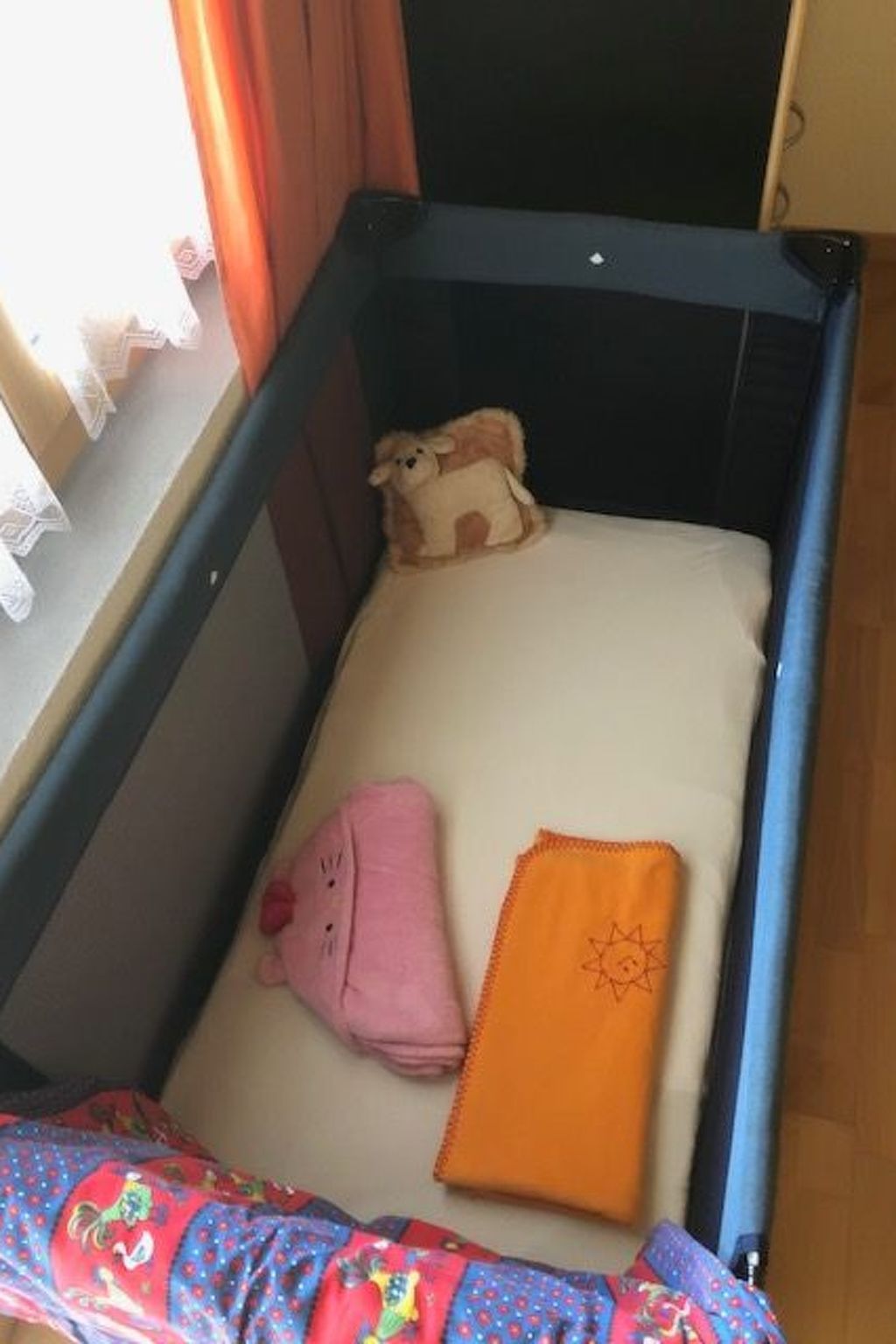 Un berceau avec un matelas, un jouet en peluche et une couverture rose.