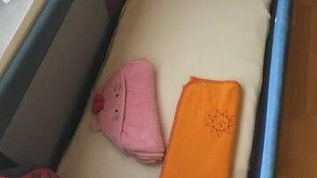 Un berceau avec un matelas, un jouet en peluche et une couverture rose.