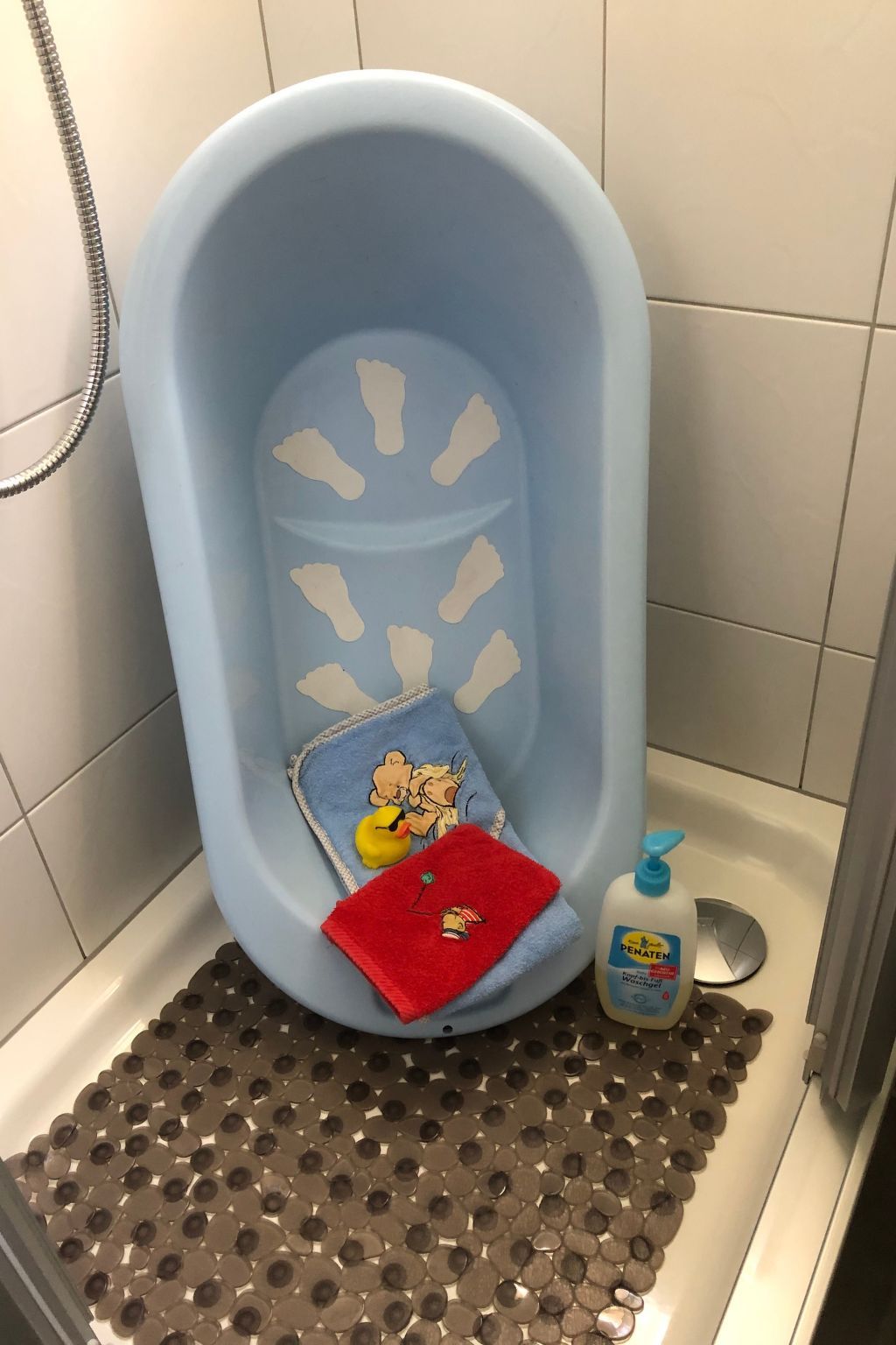 Eine Badewanne mit blauer Innenseite, ein rotes Handtuch und eine Flasche Flüssigseife.