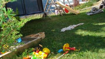 A grassy outdoor area with a slide, a swing set, and a tent.