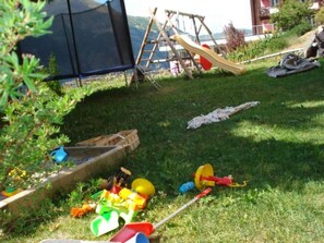 Ein grasbewachsener Außenbereich mit Rutsche, Schaukeln und einem Zelt.