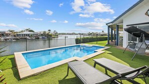 Uma piscina com espreguiçadeiras, vista para a marina e um espaço de estar coberto.
