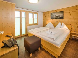 A wooden-paneled room with a bed, a desk with a telephone, and a bench. - Ferienwohnungen Lunic, AZapartments.ch, B&B, (Grächen), 1057 by Interhome (Grächen)