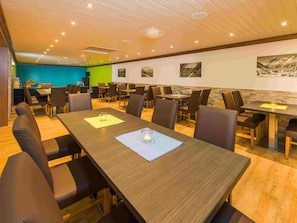 Una sala de conferències amb diverses taules i cadires, un sostre de fusta i una paret amb quadres.