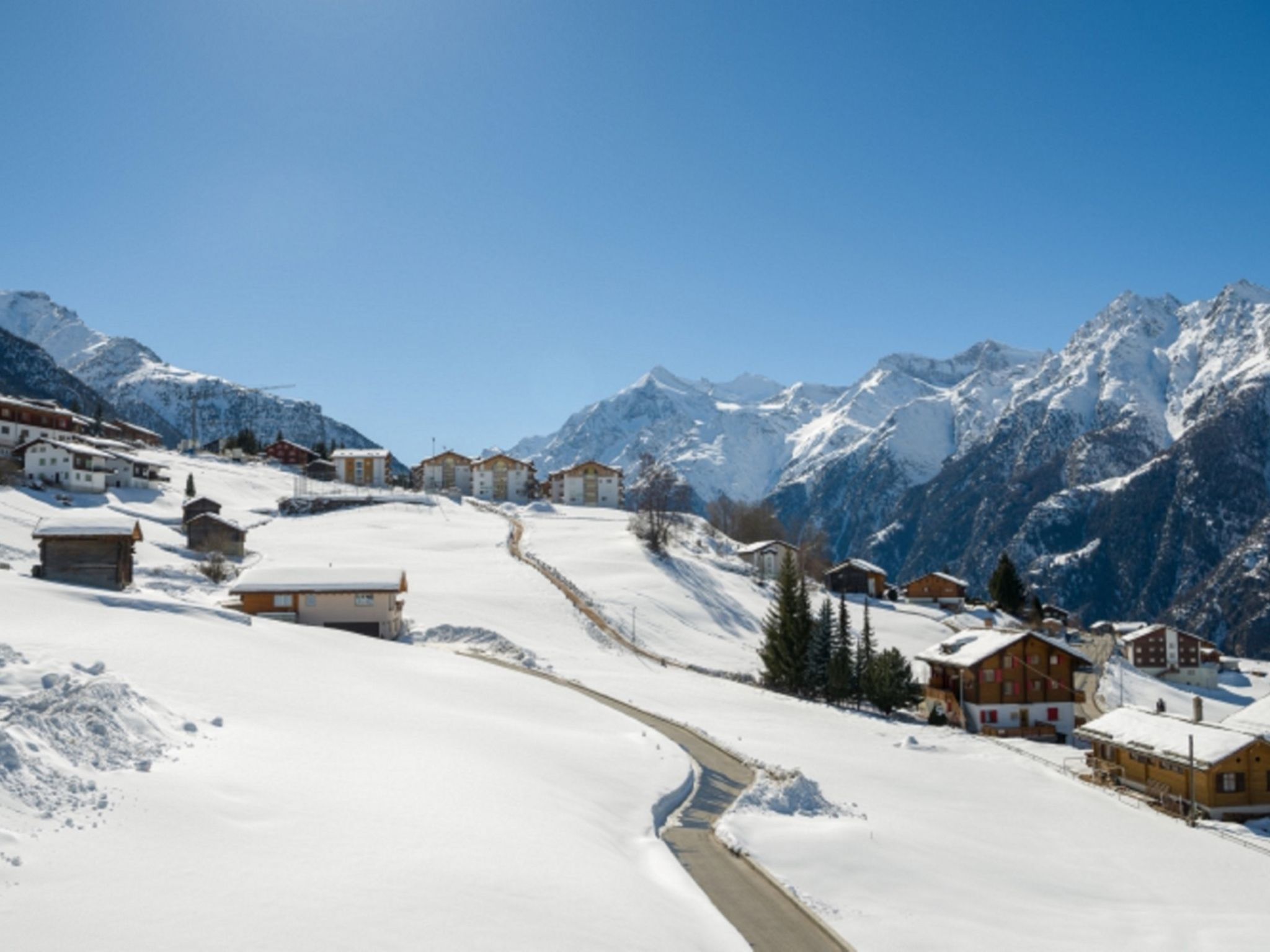 A snow-covered village with buildings and a mountain backdrop.