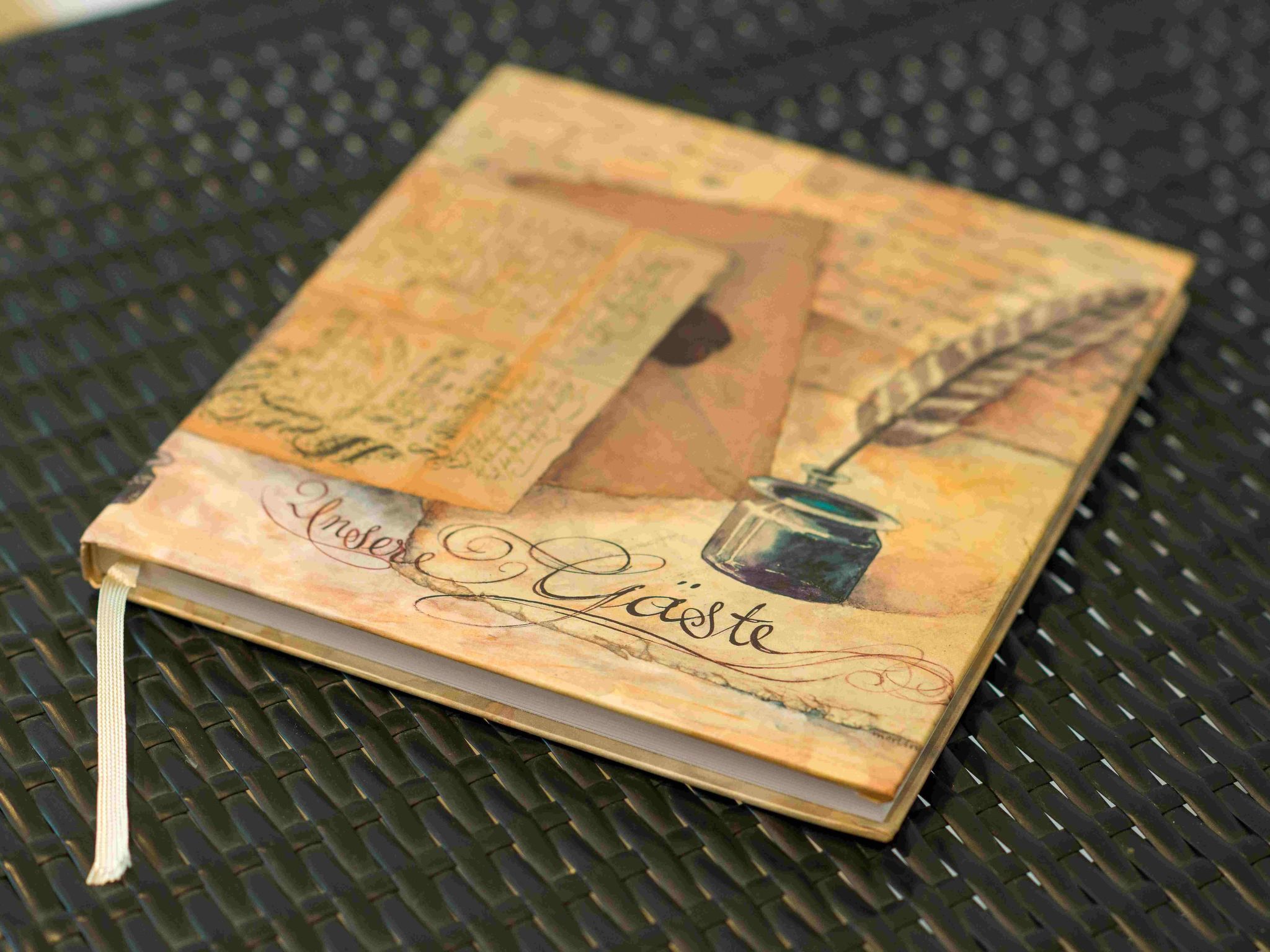 Un carnet avec une couverture décorative représentant une plume et un encrier.