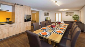 Eine moderne Küche mit Holzschränken und einem Essbereich mit einem langen Tisch, gedeckt für sechs Personen.