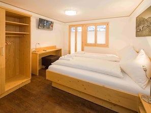 A bedroom with a wooden bed, a desk, a chair, and a wardrobe. - Ferienwohnungen Lunic, AZapartments.ch, B&B, (Grächen), 1057 by Interhome (Grächen)