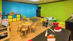 Ein Spielzimmer für Kinder mit einem runden Tisch, Stühlen und verschiedenen Spielsachen.