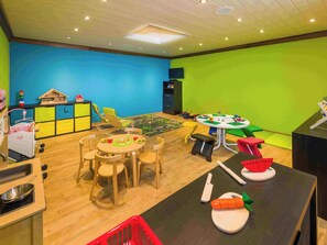 A children's playroom with a round table, chairs, and various toys. - Lunic, AZapartments.ch, B&B, (Grächen), 1057 by Interhome (Grächen)