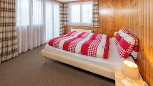 Un dormitorio con cama, cortinas, una lámpara y paredes de madera.