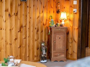 Une pièce aux murs lambrissés, contenant un meuble, une lampe et un bocal décoratif en verre.