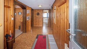 Un pasillo de madera con alfombra roja, paredes de madera y una puerta con panel de vidrio.